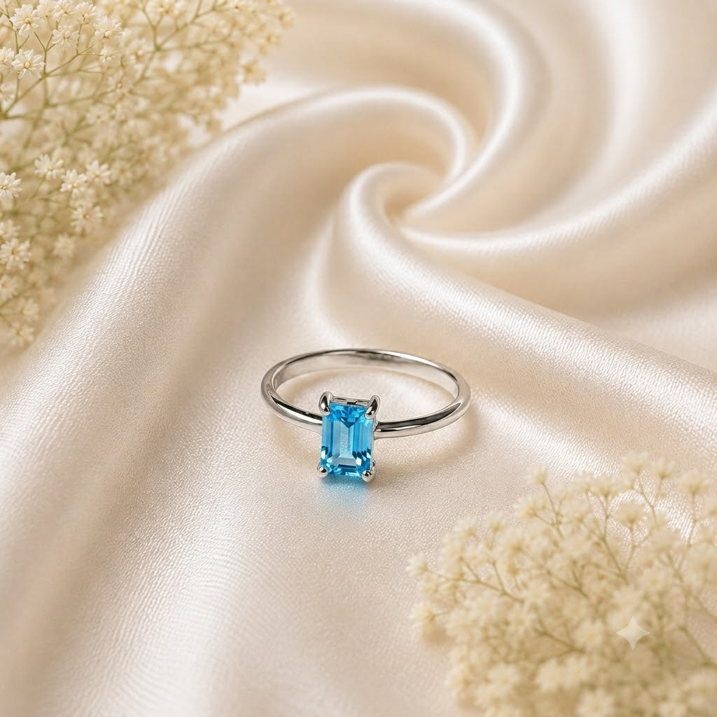 Emerald Cut Blue Topaz Ring crafted in 925 Sterling Silver with a Swiss Blue emerald cut gemstone in a four-prong solitaire setting.