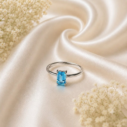 Emerald Cut Blue Topaz Ring crafted in 925 Sterling Silver with a Swiss Blue emerald cut gemstone in a four-prong solitaire setting.