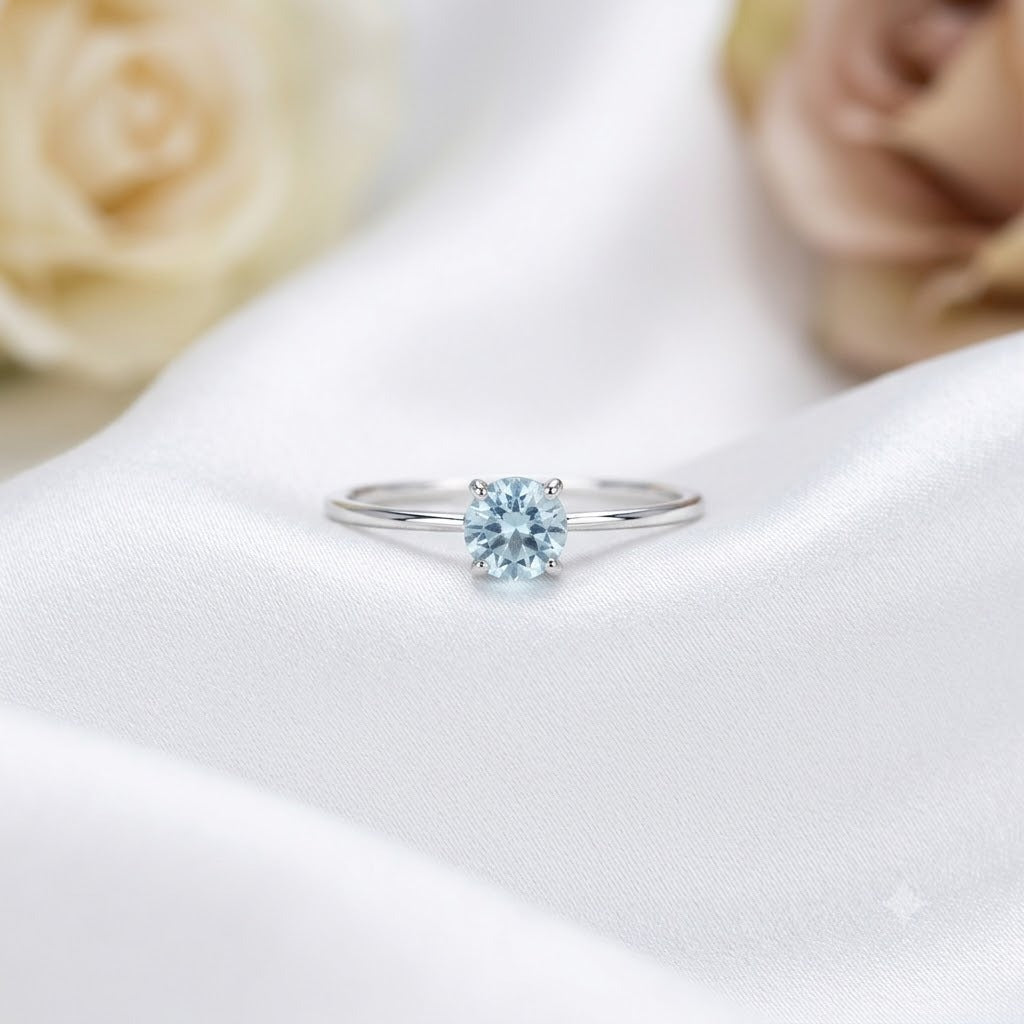 Solitaire Blue Topaz Ring crafted in 925 Sterling Silver with a round cut sky blue gemstone in a four-prong setting.