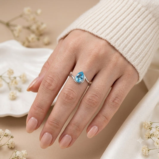 Pear Blue Topaz Ring crafted in 925 Sterling Silver with a pear cut sky blue gemstone in an open wrap setting.