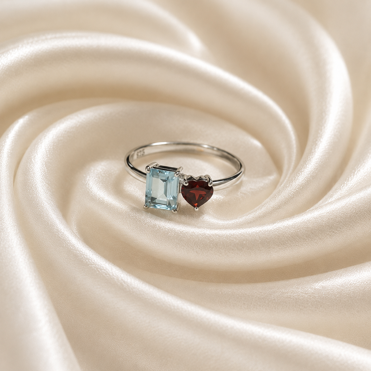 Twin Blue Topaz and Garnet Ring crafted in 925 Sterling Silver featuring an emerald cut Blue Topaz and heart cut Garnet gemstone.