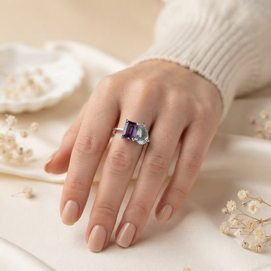 Twin Amethyst and Blue Topaz Ring crafted in 925 Sterling Silver featuring an emerald cut Amethyst and heart cut Blue Topaz gemstone.