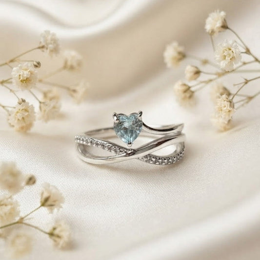 Heart Blue Topaz Ring crafted in 925 Sterling Silver with a heart cut sky blue gemstone and crossover pavé band.