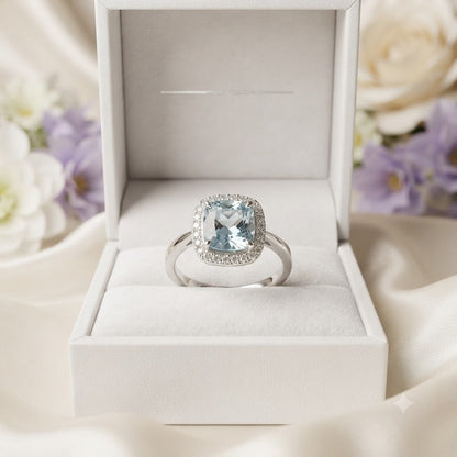 Halo Blue Topaz Ring crafted in 925 Sterling Silver with a cushion cut sky blue gemstone surrounded by a sparkling halo in a four-prong setting.