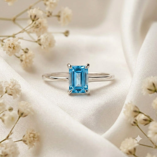 Emerald Cut Blue Topaz Ring crafted in 925 Sterling Silver with a Swiss Blue emerald cut gemstone in a four-prong solitaire setting.