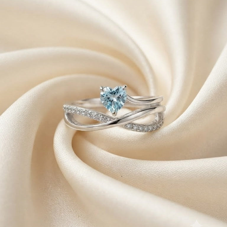 Heart Blue Topaz Ring crafted in 925 Sterling Silver with a heart cut sky blue gemstone and crossover pavé band.