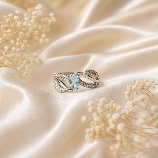 Oval Blue Topaz Ring crafted in 925 Sterling Silver with an oval cut sky blue gemstone and intertwined pavé accented band.