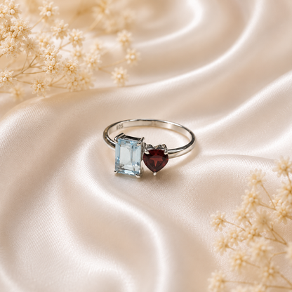 Twin Blue Topaz and Garnet Ring crafted in 925 Sterling Silver featuring an emerald cut Blue Topaz and heart cut Garnet gemstone.