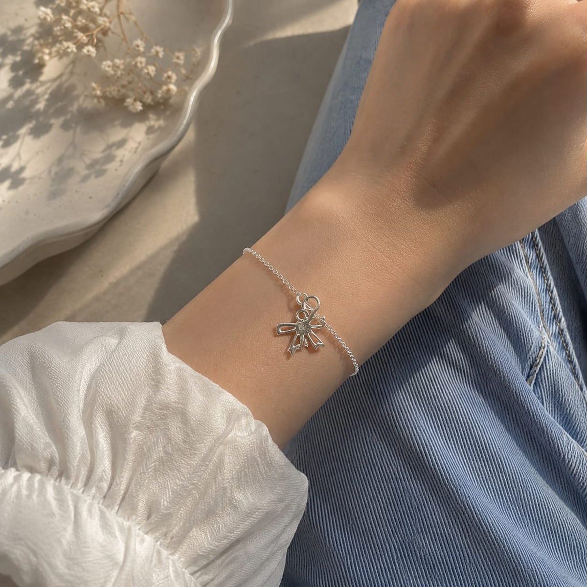 925 Sterling Silver Ribbon Bow Charm Pendant Resting on a Neutral Ceramic Dish