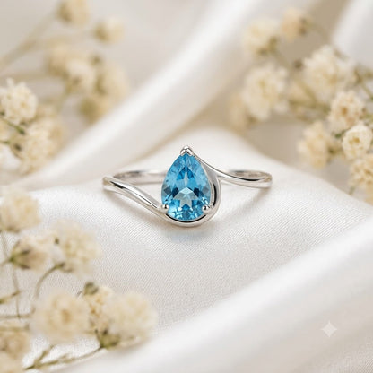 Pear Blue Topaz Ring crafted in 925 Sterling Silver with a pear cut sky blue gemstone in an open wrap setting.
