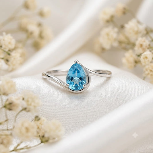 Pear Blue Topaz Ring crafted in 925 Sterling Silver with a pear cut sky blue gemstone in an open wrap setting.