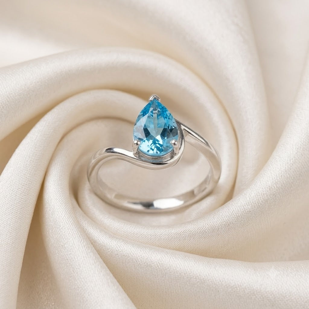 Pear Blue Topaz Ring crafted in 925 Sterling Silver with a pear cut sky blue gemstone in an open wrap setting.