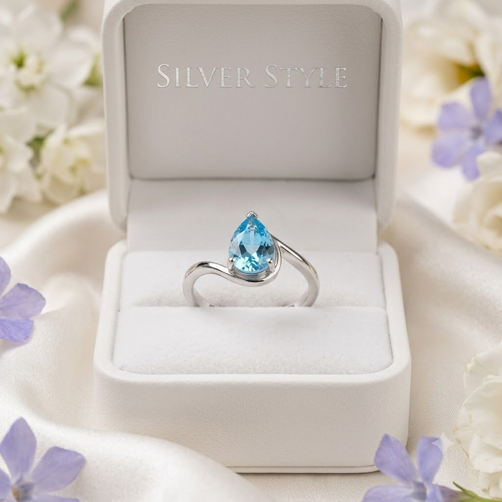 Pear Blue Topaz Ring crafted in 925 Sterling Silver with a pear cut sky blue gemstone in an open wrap setting.