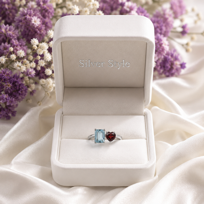 Twin Blue Topaz and Garnet Ring crafted in 925 Sterling Silver featuring an emerald cut Blue Topaz and heart cut Garnet gemstone.